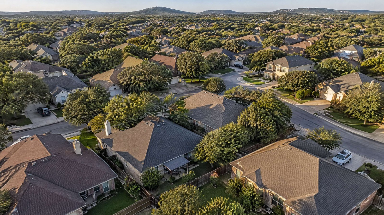 Aerial view of shingle roofs and live oaks in a San Antonio neighborhood